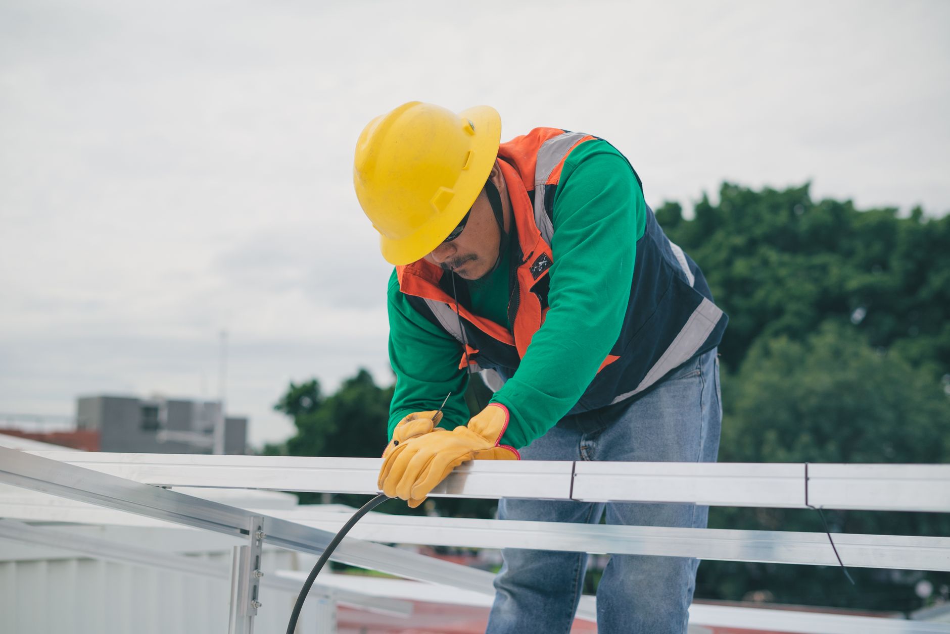 A close-up of a roofer's hands meticulously sealing a seam on a new roof installation, with a clear view of a Lemon Grove neighborhood in the background.